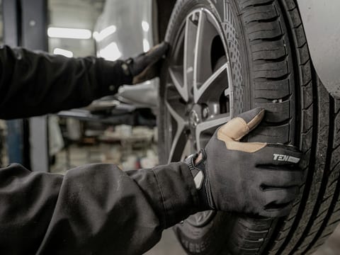 Mechanic in work gloves refitting a wheel